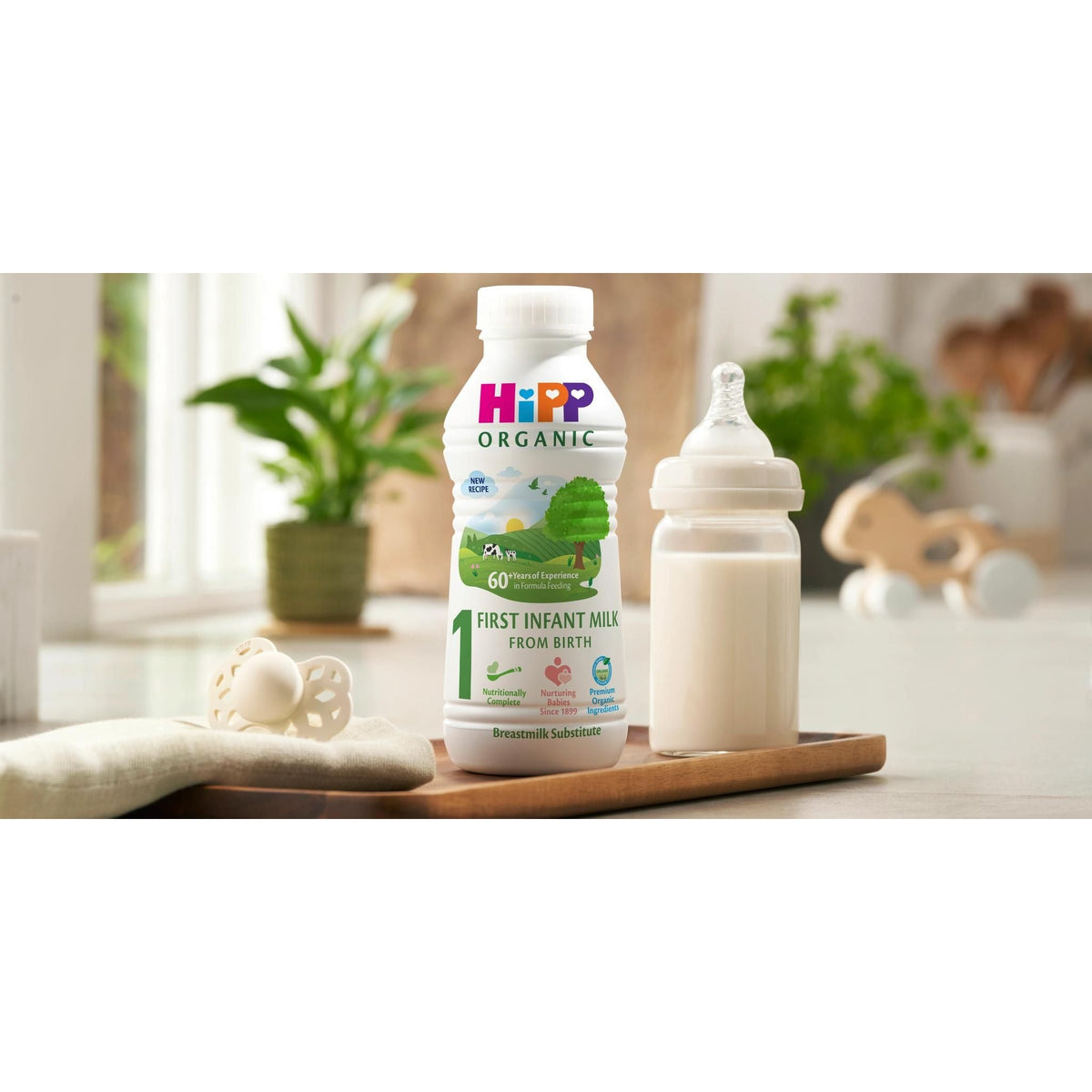 HiPP Organic baby milk bottle and container on a wooden tray with a blurred background